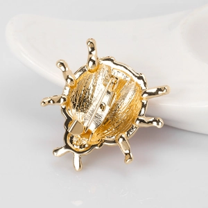 Back view of gold-tone ladybug brooch showing secure safety pin clasp and metal finish
