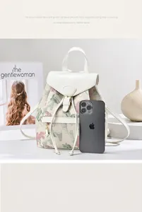 Floral backpack for women with white leather flap shown next to an iPhone for size scale