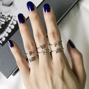 Set of 6 handmade 925 sterling silver letter rings worn on hand with blue nail polish