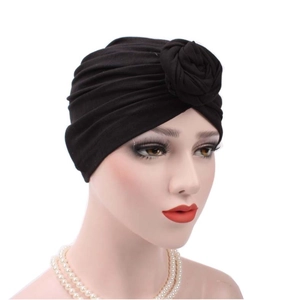 Black pleated cotton turban hat for women featuring a floral knot detail in a side view