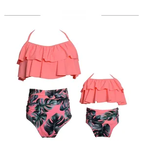Detail view of matching mother and daughter two-piece swimsuits with pink ruffles and leaf prints