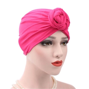 Detail of rose red cotton turban hat with a decorative flower knot on white background