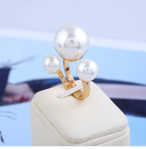 Detail of gold pearl ring featuring three white pearls on a modern jewelry display stand