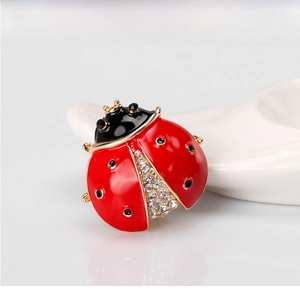 Macro view of ladybug brooch featuring red enamel, black spots and white rhinestones