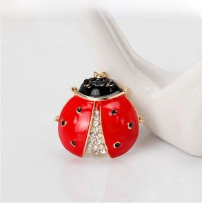 Macro shot of ladybug brooch with red enamel wings and crystal inlay on ceramic