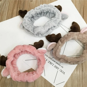 Plush Christmas reindeer antler headbands in grey, pink and brown on wooden background
