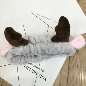 Close-up of a plush grey headband with brown antlers and pink ears on wooden background