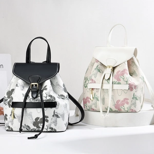 Women's floral and pine print drawstring backpacks with leather trim on white platforms