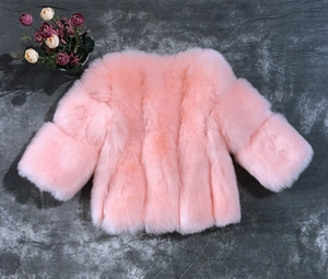Dettaglio dell'abbigliamento in pelliccia sintetica rosa con texture soffice e maniche 3/4
