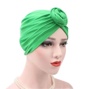 Detail of green pleated cotton turban hat featuring a large decorative front knot design