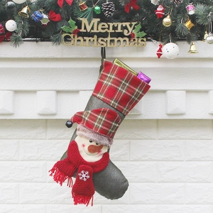 Christmas stocking with snowman and plaid cuff hanging on fireplace for holiday decor