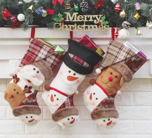 Calze natalizie in peluche con Babbo Natale e pupazzo di neve su un caminetto