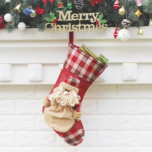 Festive red plaid Christmas stocking with 3D Santa Claus figure hanging on fireplace