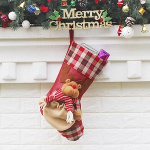 Classic red plaid Christmas stocking with 3D reindeer plush hanging on white fireplace