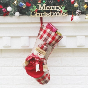 Christmas stocking with red plaid and snowman doll hanging on a festive mantelpiece