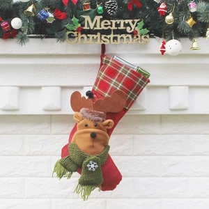 Christmas stocking with plush reindeer hanging on a festive decorated white mantelpiece