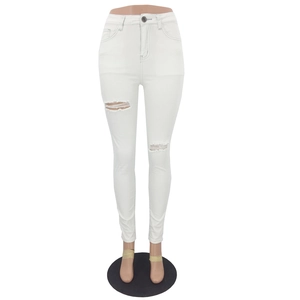 Detail of white high-waisted distressed skinny jeans with ripped knee design on a mannequin