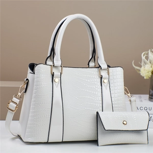 Detail of white crocodile embossed leather tote bag with gold hardware and small pouch