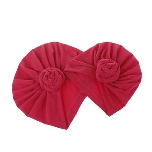 Detail of red baby turban hats with handmade rose knots and soft knitted texture