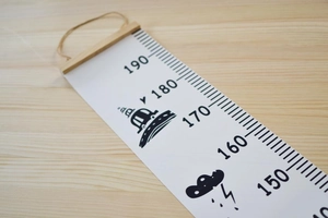 Close-up of wooden frame and canvas scale with UFO and cloud patterns for height chart