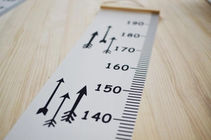 Detail of wooden hanging ruler with black printed numbers 140 to 190 cm on canvas