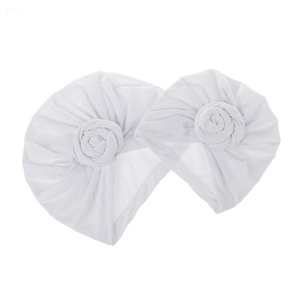 Close-up of two white baby turban hats with large soft fabric flower knot details