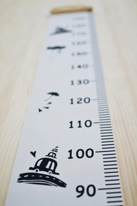 Close-up of canvas height chart with cartoon icons and wooden hanging bar detail