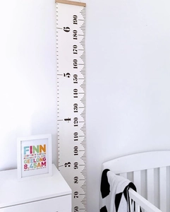 Detail of wooden canvas growth chart with feet and cm scales in a cozy nursery