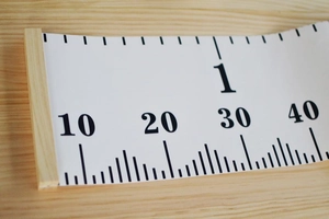 Close-up of wooden hanging rod and canvas material on cartoon growth chart for kids
