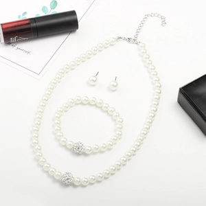 Détail de l'ensemble collier, bracelet et boucles d'oreilles en perles blanches et cristal