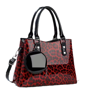 Red leopard print patent leather handbag with black handles and small round charm