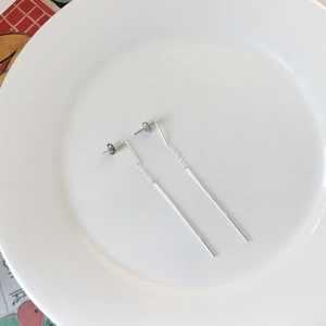 Minimalist S925 sterling silver long chain threader earrings on a white ceramic plate