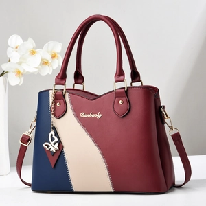 Sac à main élégant patchwork tricolore avec poignées et breloque papillon décorative