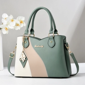 Détail du sac à main tricolore en cuir avec charm papillon et logo doré brillant