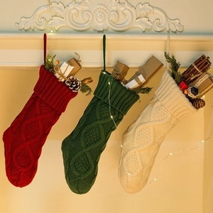 Three festive knit Christmas stockings in red, green, and cream on a warm mantel decor