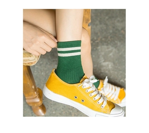 Detail shot of green mid-calf cotton socks with white stripes worn with canvas sneakers