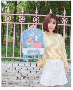 Blue and white PU leather ita bag with large bow detail shown in an outdoor lifestyle setting