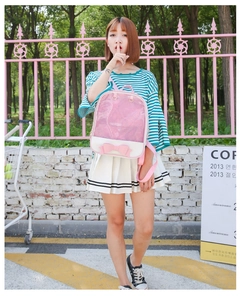 Detail of pink transparent glitter backpack with a large bow decoration in an outdoor setting