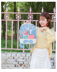 Close-up of a blue and white bow backpack with clear front window for pins
