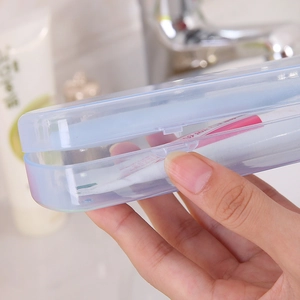 Light blue translucent portable toothbrush case held by hand in a bathroom setting