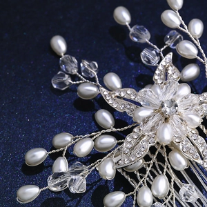 Elegant bridal hair comb with crystal flowers and white pearls on a sparkling blue background