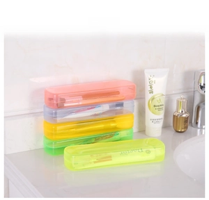Detail view of colorful translucent plastic travel cases for toothbrushes on white marble