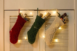 Close-up of knit Christmas stockings in red, green and beige hung with festive decor