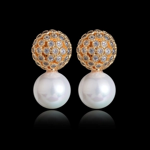 Elegant gold hollowed zircon ball and large round white pearl earrings on black background