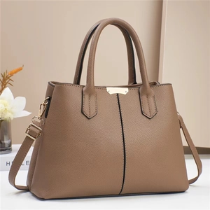Detail of brown litchi pattern leather handbag with golden clasp and dual handles