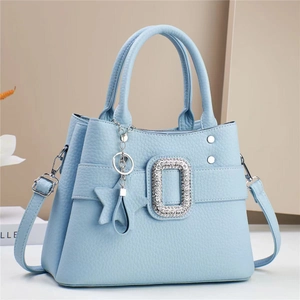 Detail of light blue crossbody bag featuring a sparkling crystal buckle and star charm