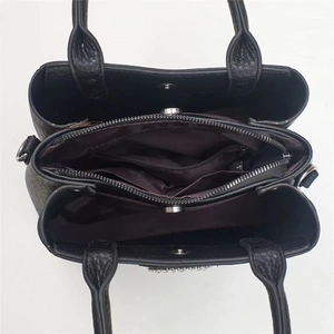 Interior view of black litchi leather handbag with multiple compartments and purple lining