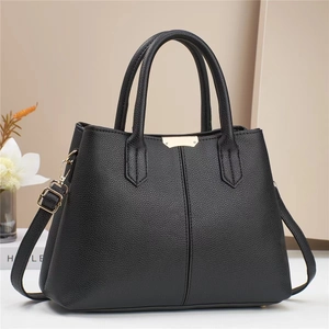 Close-up of black lychee grain leather handbag with elegant gold metal hardware and texture
