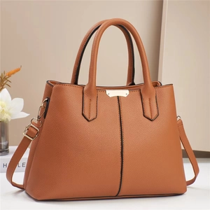 Detail view of brown pebbled leather texture and silver hardware on a women's tote bag