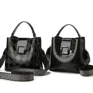 Detail of black patent leather bucket bags with crocodile pattern and fabric strap
